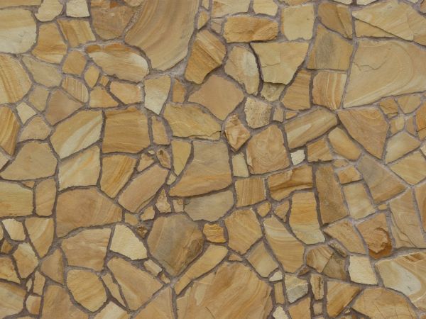 Peach-colored rough flat stone set in dark grey concrete.